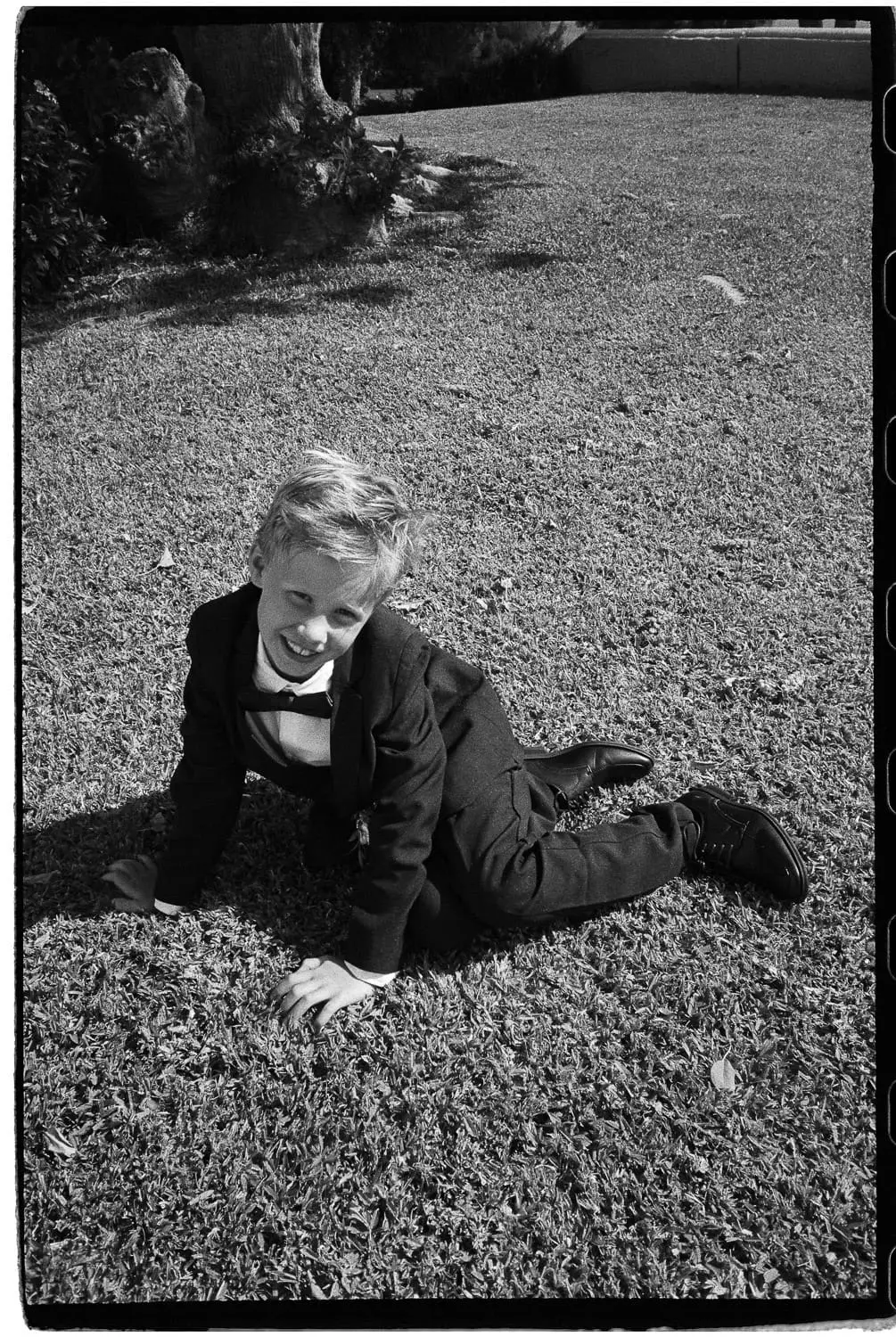 Niño con traje jugando en el césped durante una boda en el Hotel Montecastillo, Jerez, fotografiado en película
