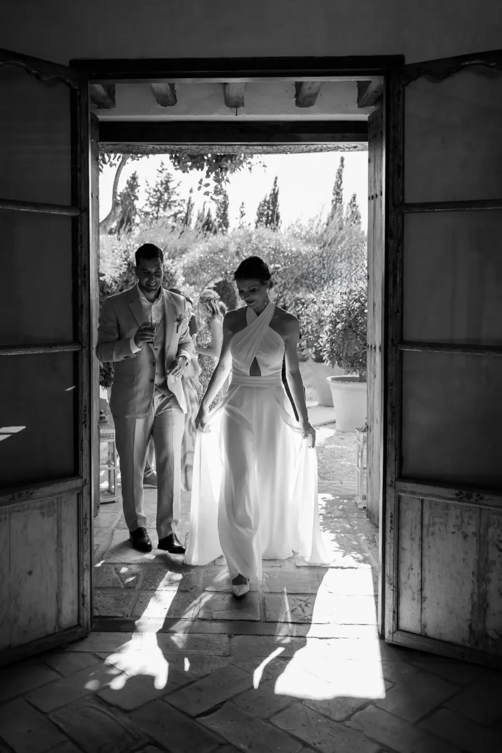 Novios entrando por una puerta llena de sol en Casa La Siesta, Vejer, en blanco y negro